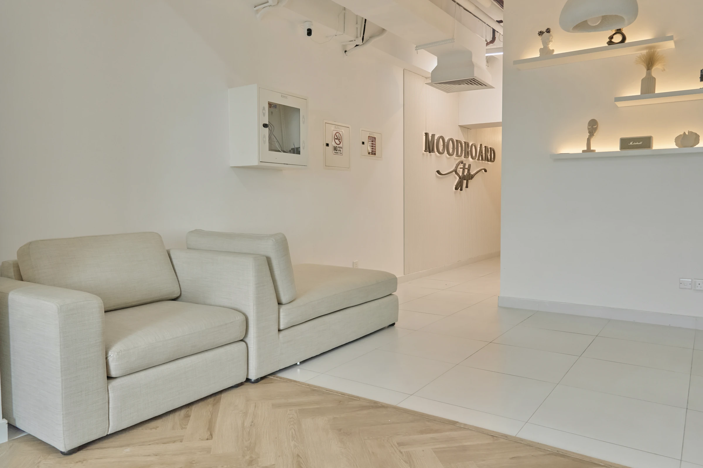 The lounge: a cream sofa, lit shelves with ceramics and the Moodboard sign on the wall